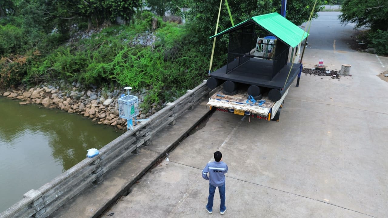 รถบรรทุกขนแพเครื่องสูบน้ำหลังคาเขียวมาถึงริมตลิ่ง — งานประกอบติดตั้งแพ T.K.M. Aquatic