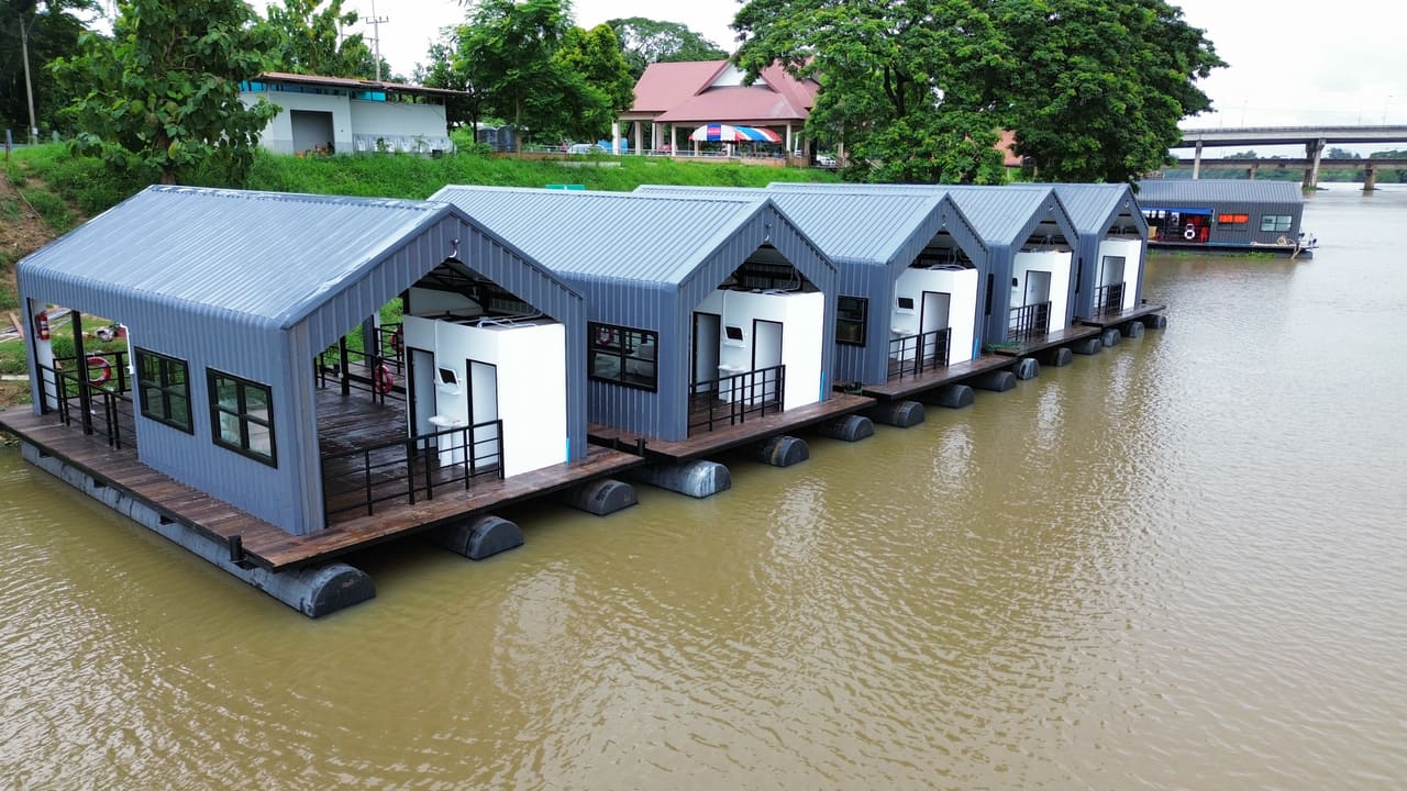 แพที่พักหลังคาจั่วสีเทาเรียงต่อกันบนแม่น้ำ มุมสูงด้านข้าง — แพที่พักล่องในลำน้ำ เขื่อน แม่น้ำ T.K.M. Aquatic