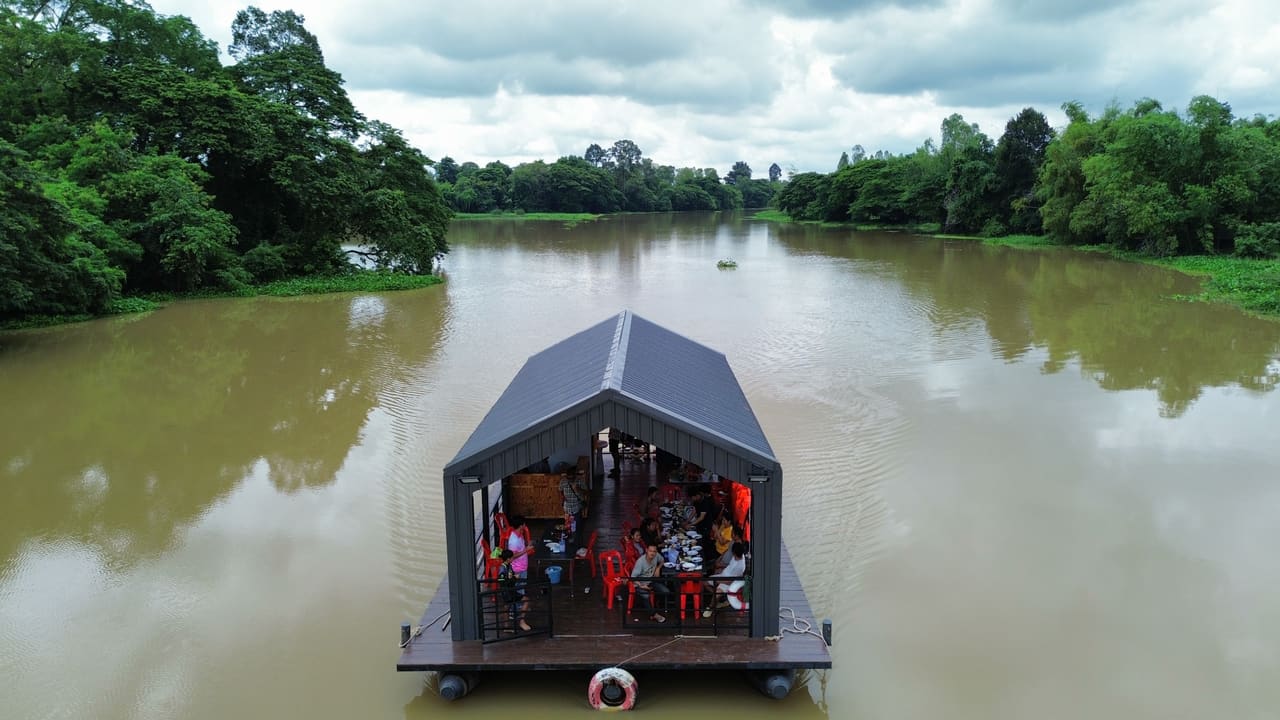 แพที่พักลอยน้ำหลังคาจั่วกลางลำน้ำ มีผู้ใช้งานอยู่ภายใน — แพที่พักล่องในลำน้ำ เขื่อน แม่น้ำ T.K.M. Aquatic
