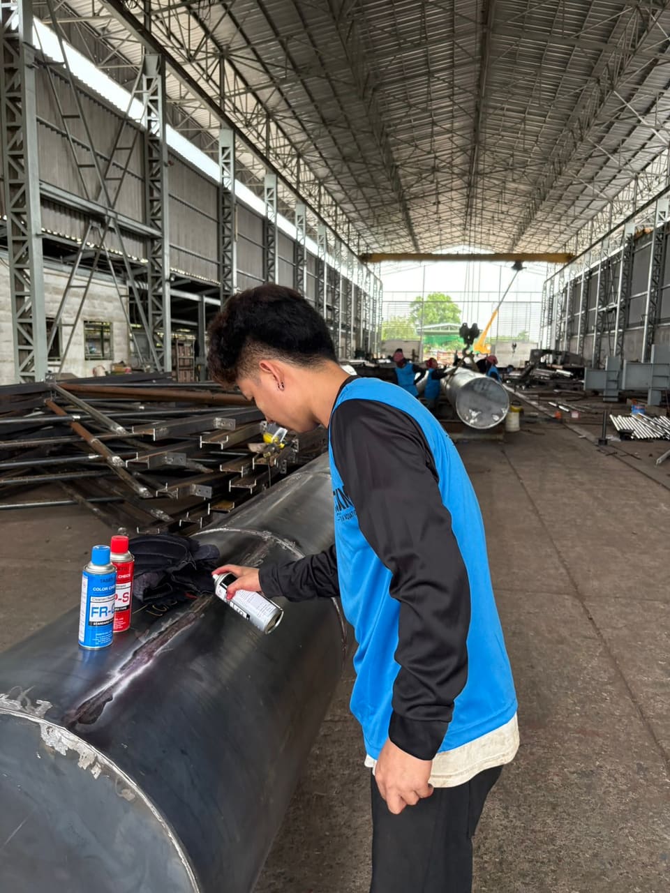 ช่างพ่นน้ำยาตรวจแนวเชื่อม (Penetrant) บนตัวทุ่น — ขั้นตอนการผลิตทุ่นเหล็ก T.K.M. Aquatic
